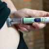 A woman is shown using an injection pen with the word 