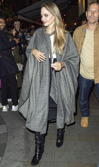 Angelina Jolie wearing a gray coat, skirt, and knee boots