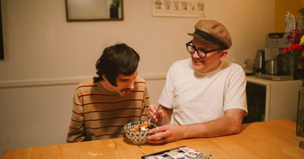 A man helping an autistic man eat https://www.autismparentingmagazine.com/homes-for-autistic-adults/