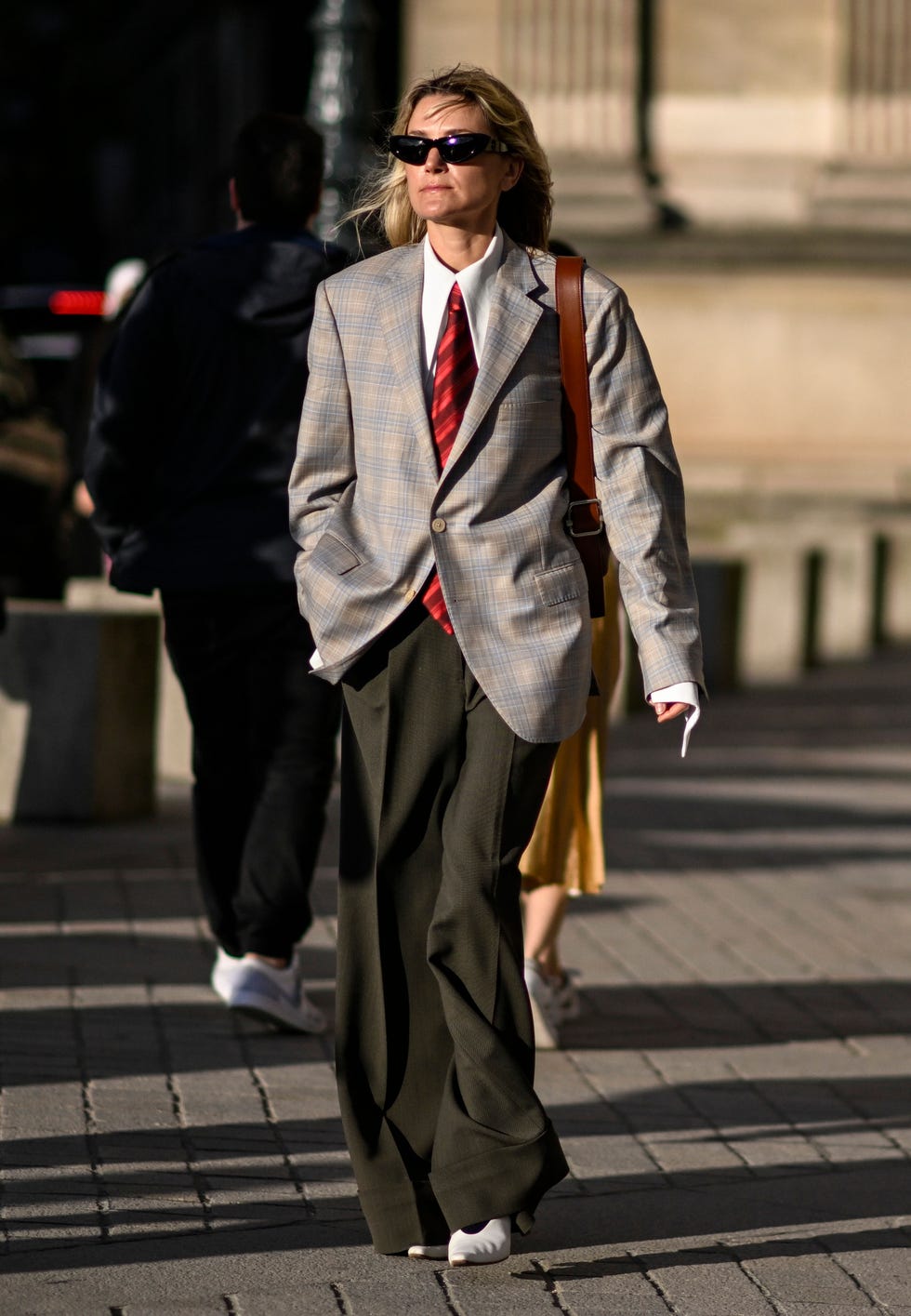 paris, france october 01 a guest is seen wearing a gray jacket, white shirt, red tie, gray pants and white heels with black sunglasses outside the louis vuitton show during womenswear springsummer 2025 as part of paris fashion week on october 01, 2024 in paris, france photo by daniel zuchnikgetty images