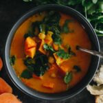 curried sweet potato soup with chopped sweet potatoes, chickpeas and swiss chard in a blue bowl.