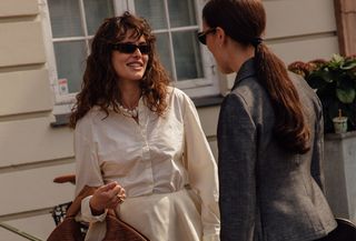 two women looking at each other in stylish clothes